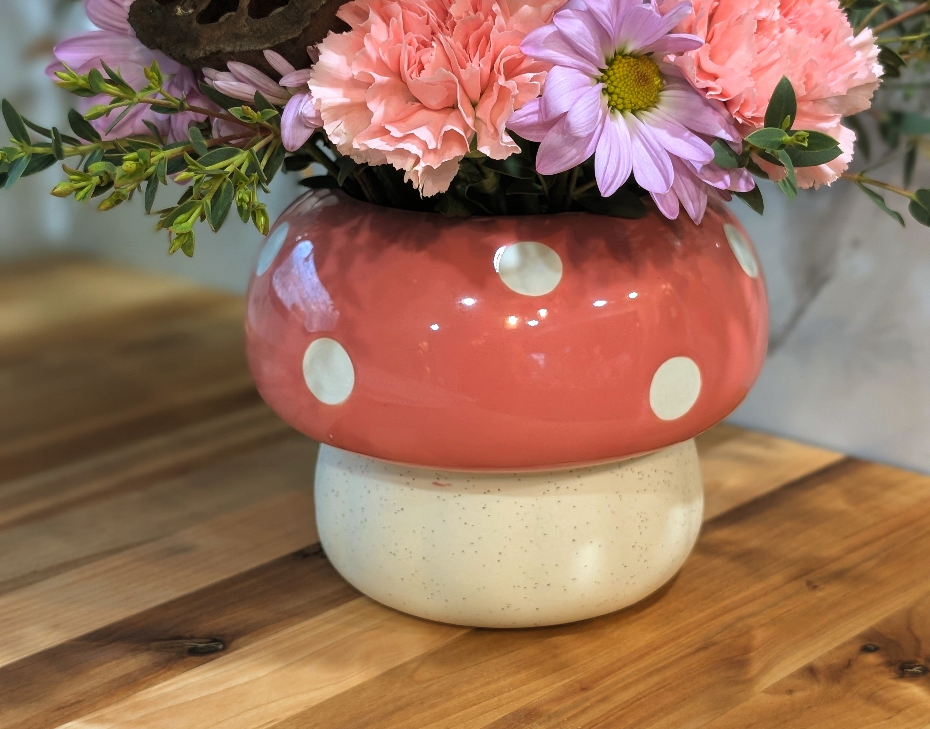 Pink polka-dot mushroom keepsake vase filled with roses, carnations, daisies, and garden-style seasonal flowers.